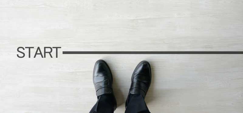 Two feet in business shoes standing behind a line marked START.