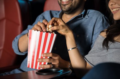 Two moviegoers share popcorn.