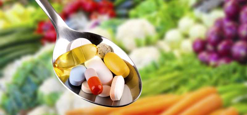 A spoon full of various vitamins.