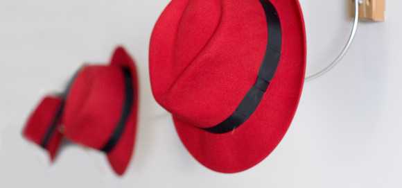 Red hats on hooks on the wall.