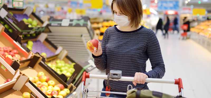 Woman grocery shopping in a surgical mask.