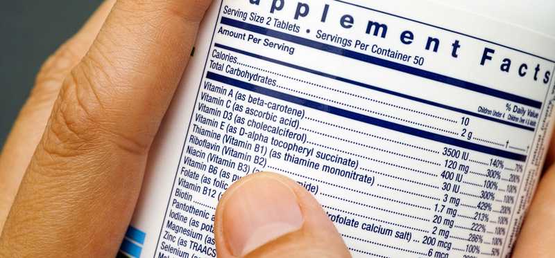 Hands hold a jar of multivitamins with the nutrition info facing out.