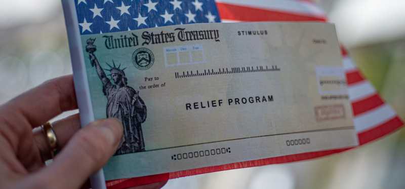 Relief check being held in front of U.S. flag