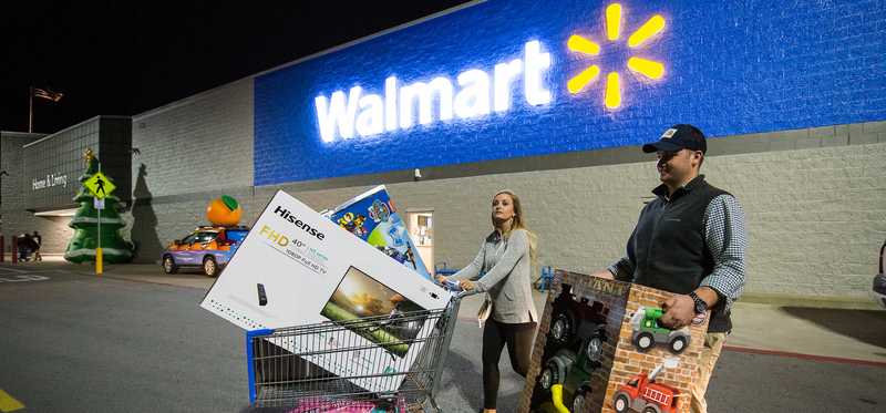 Walmart shoppers on Black Friday in the parking lot with their purchases.