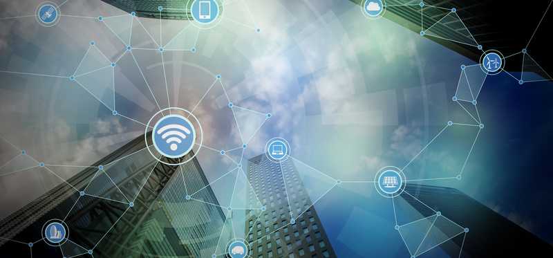 A digital rendering of skyscrapers with internet symbols like Wifi and bluetooth superimposed over it in a web