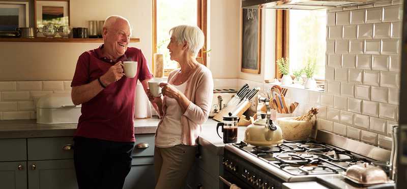 Two people stand in a kitchen while drinking coffee.