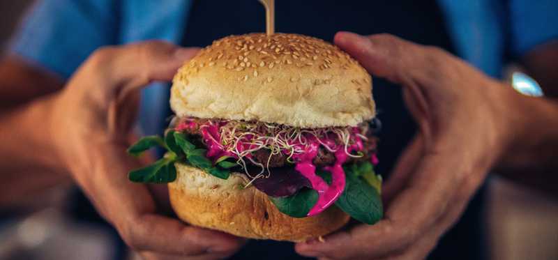 Hands holding a thick veggie burger.