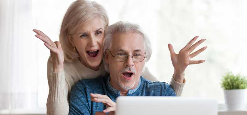 Couple happily surprised in front of laptop