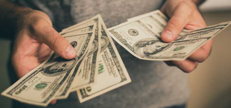 Person holding hundred dollar bills.