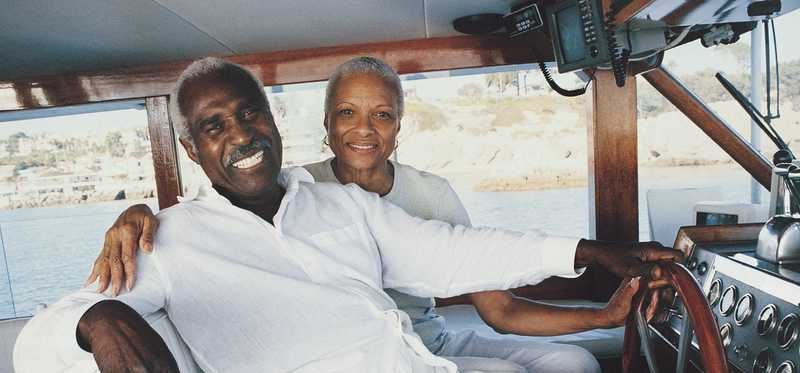 Two people smiling at helm of boat.