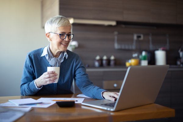 Mature woman sitting at kitchen table looking at computer