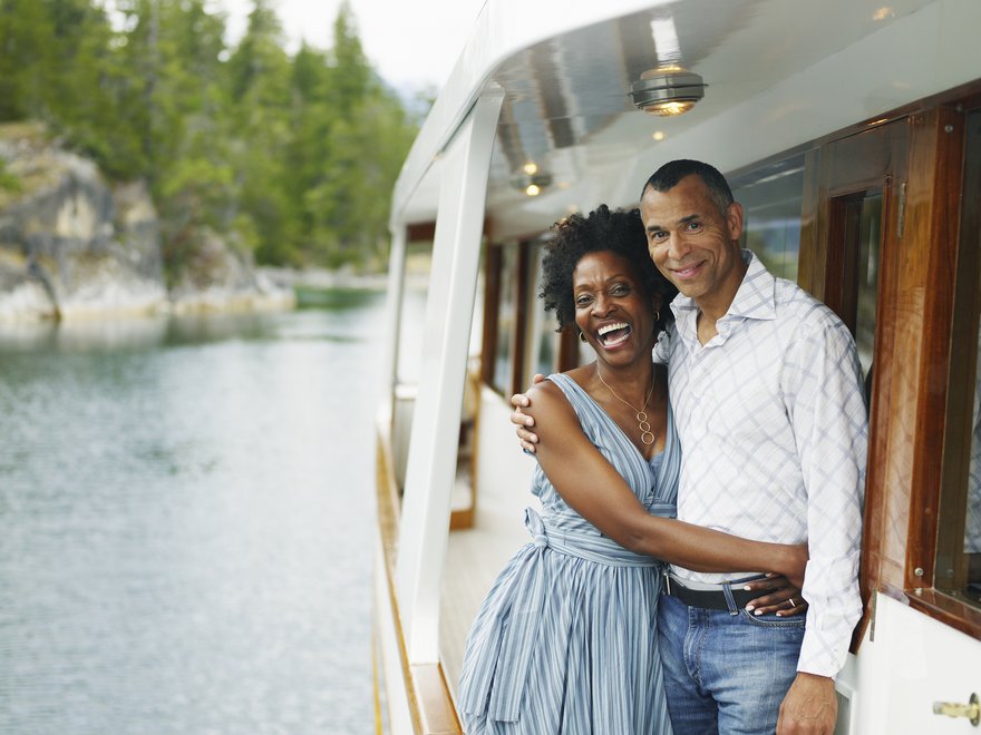 Two people standing on deck of boat on a lake.
