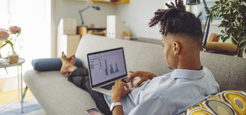 Person lying on couch with laptop screen showing charts.