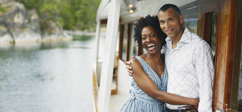 Two people standing on deck of boat on a lake.