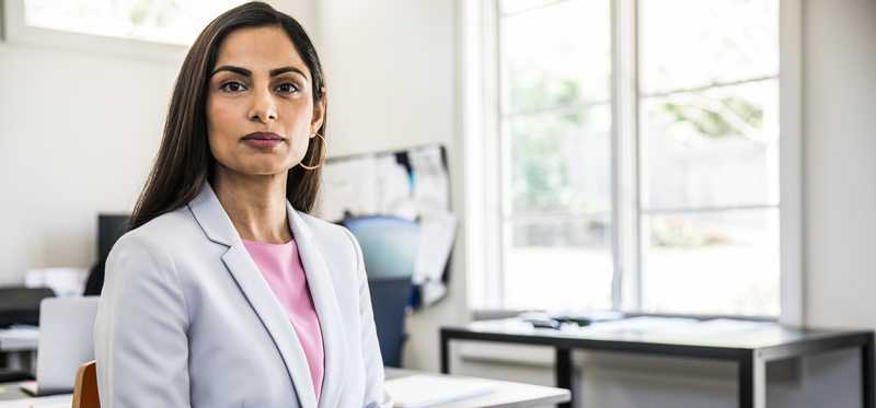 Businessperson looking thoughtfully while seated in sunny office.