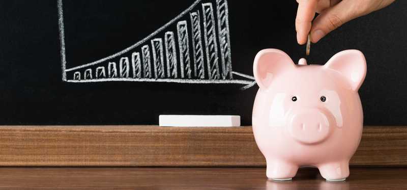 A piggy bank in front of a blackboard.