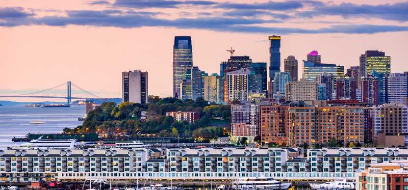 Jersey City's skyline with tall buildings and residential buildings along the river.