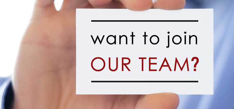 Hand holding small sign that says Want to Join Our Team.