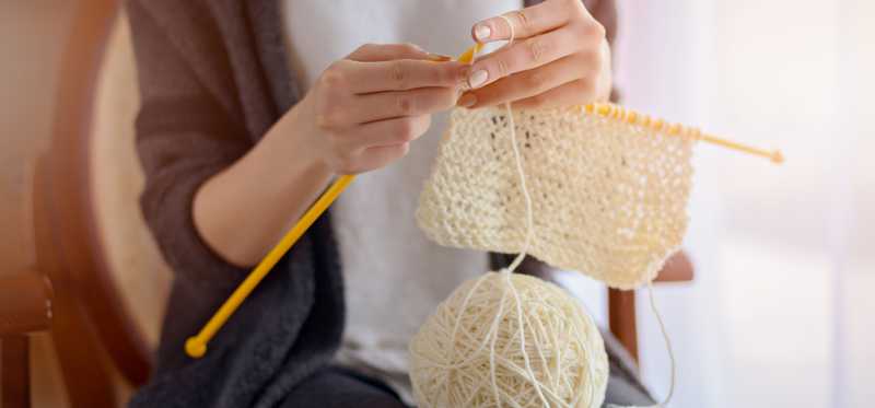 A close-up of a person's hands knitting.