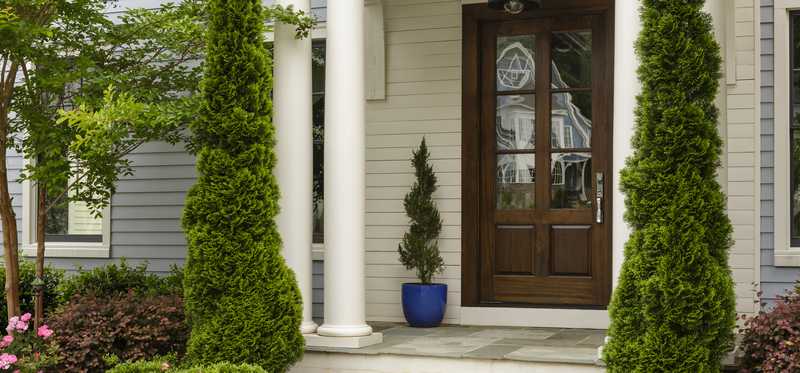 Topiary columns and landscaping at home's entrance.