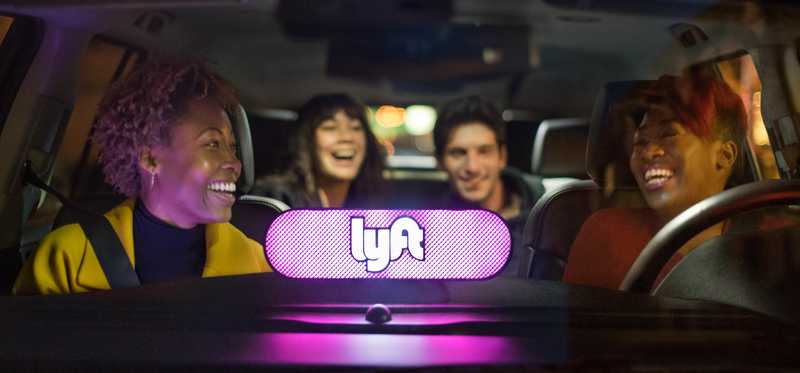 Lighted Lyft logo in windshield with drivers and passengers in vehicle laughing