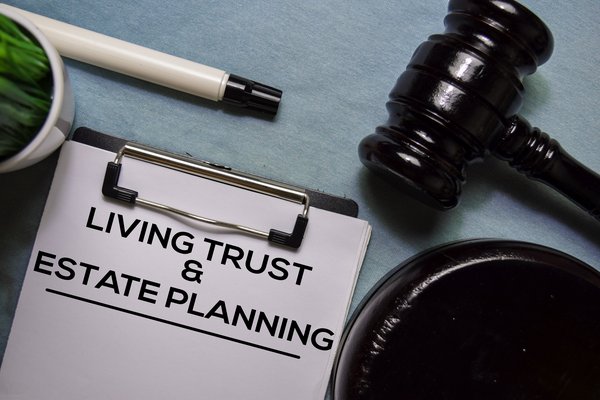 A clipboard with living trust and estate planning written on the paperwork it's holding.