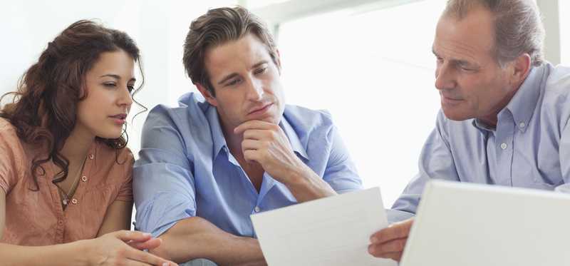Two people looking over financial documents with an advisor.