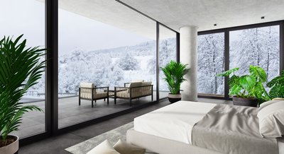 Luxury bedroom with glass windows overlooking snowy mountain.