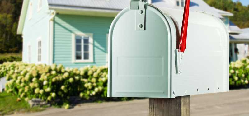A sea-foam green mailbox in front of a lovely matching home.