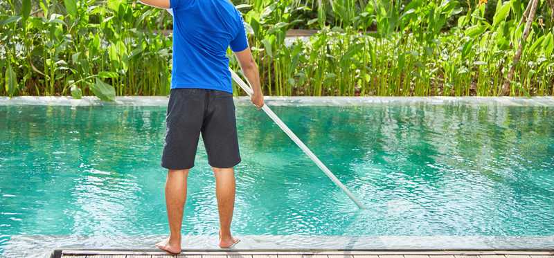 Man cleaning swimming pool.
