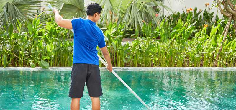 Person cleaning swimming pool.