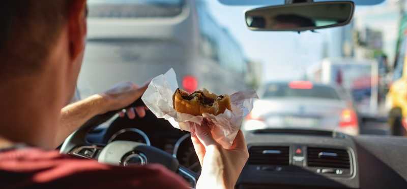 Person eating hamburger while driving.