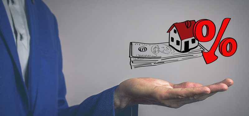 Man holding hand beneath illustration of home with money and percent sign.