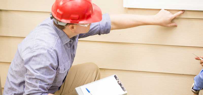 Person in hard hat pointing at siding.