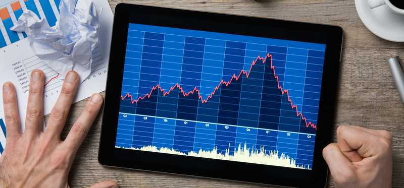 Person looking at declining share price chart on tablet is pounding fist on table.