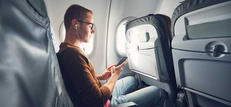 Young man uses his smartphone on an airplane.