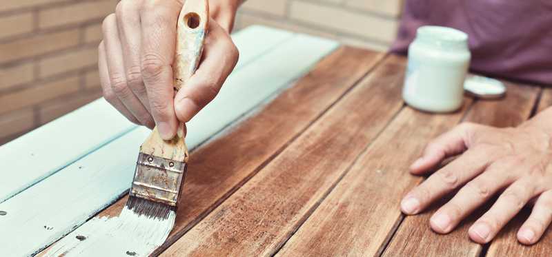Person painting old wooden table.