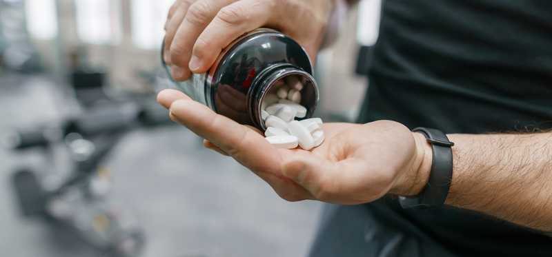 Man pouring supplements out of bottle.