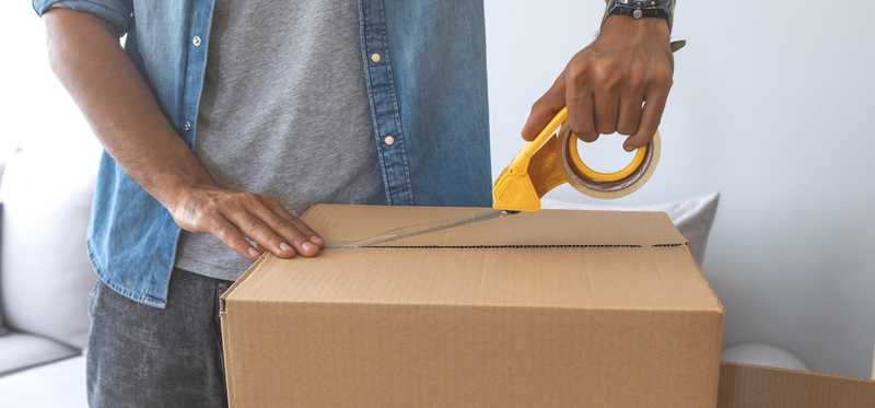 Man taping a cardboard box.