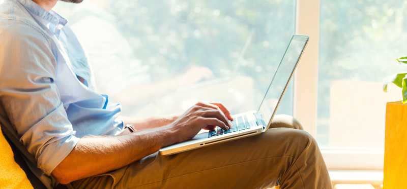 Man using laptop on his lap.