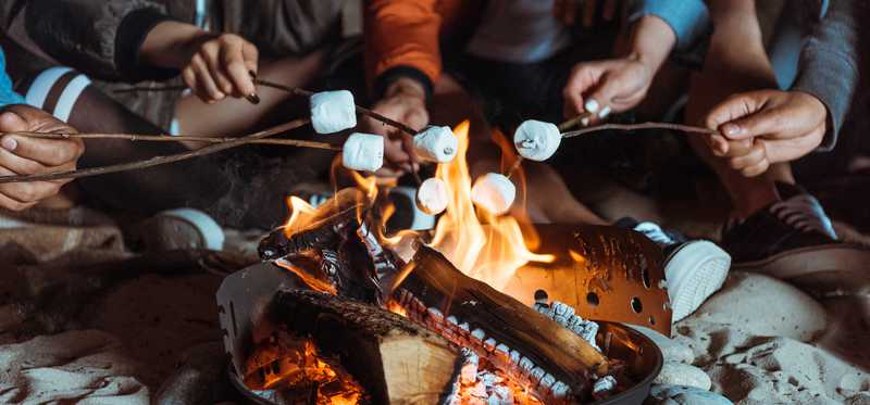 A group of people roasting marshmallows over a fire.