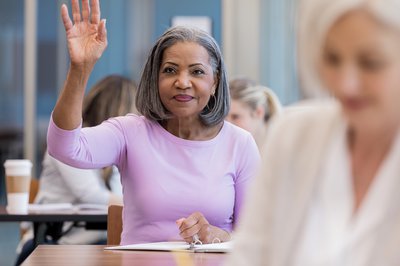 Adult raising hand in classroom.