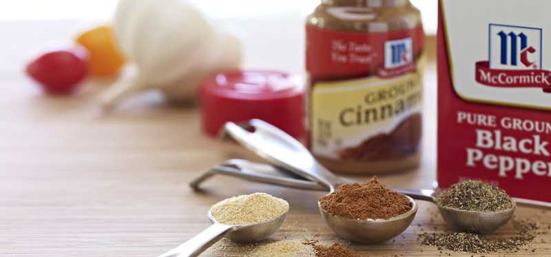 McCormick cinnamon and pepper bottles next to measuring spoons filled with spices