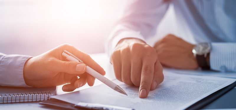 Two people sit around a piece of paper.