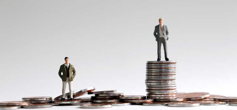 Miniature people standing on stacks of coins
