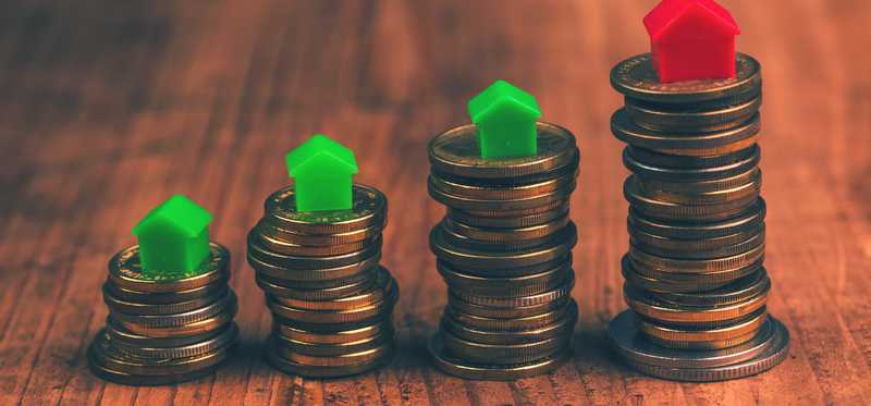 Stacks of coins with monopoly red and green houses on top of each pillar.