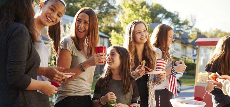 Neighbors smiling and eating at a block party.