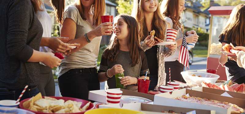 Neighbors smiling and eating at a block party.