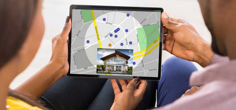 A couple looks at a tablet and sets their geographical search parameters for a new home.