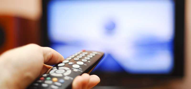 A remote control is pointed at a big-screen television.